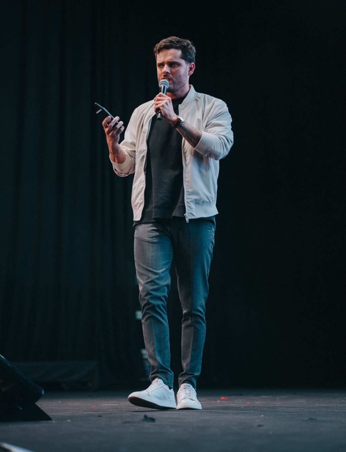 Thomas Macedo caminhando pelo palco durante palestra